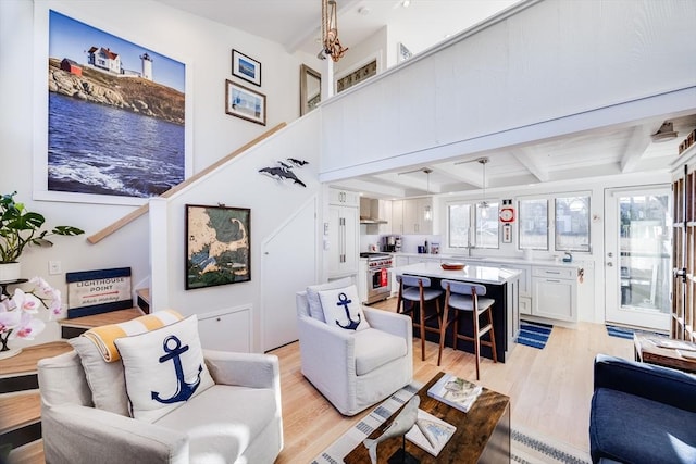 living room featuring beamed ceiling, sink, and light hardwood / wood-style flooring