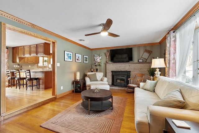 living room with ornamental molding, a fireplace, and light wood-type flooring