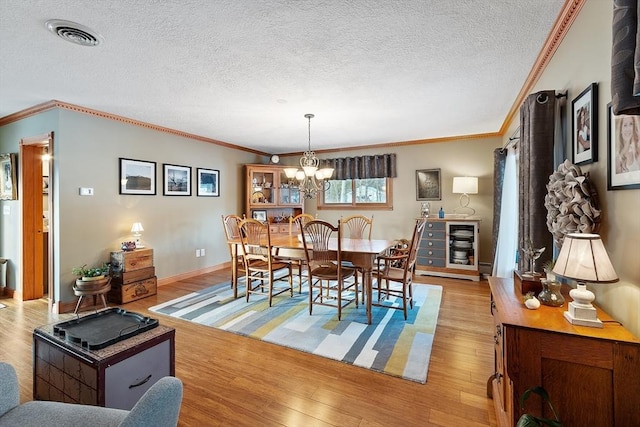 dining room with crown molding, an inviting chandelier, a textured ceiling, and light wood-type flooring