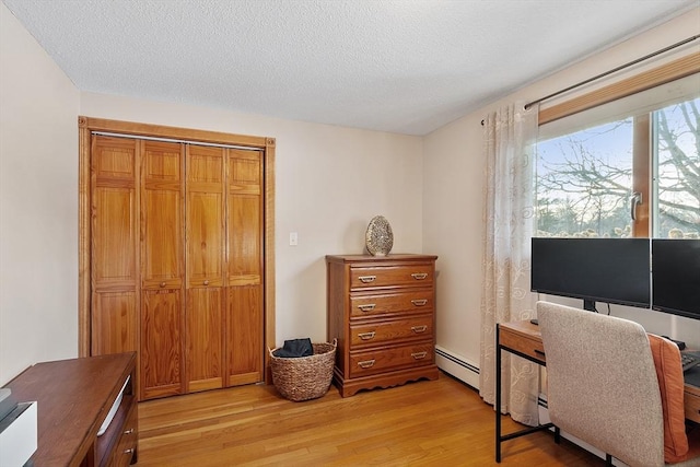 office featuring baseboard heating, light hardwood / wood-style floors, and a textured ceiling