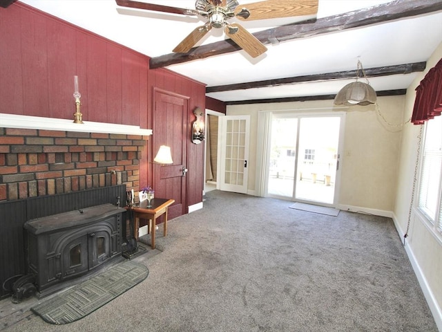 25 Rollinson Rd, Worcester, MA 01606 - carpeted living area featuring beam ceiling, a wood stove, baseboards, a ceiling fan, and wooden walls