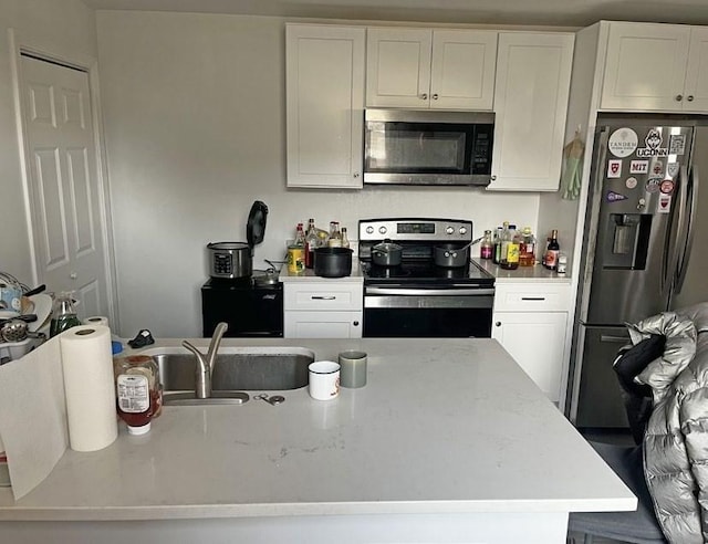 kitchen with white cabinets, a center island with sink, stainless steel appliances, and a sink