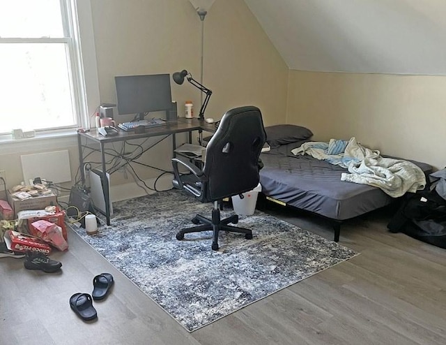 bedroom with vaulted ceiling and wood finished floors