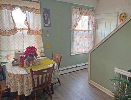 dining area with a baseboard heating unit, baseboards, and wood finished floors