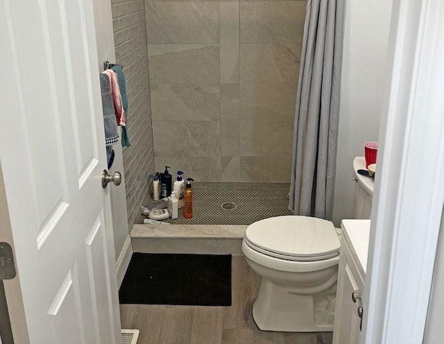 bathroom with vanity, a shower stall, toilet, and wood finished floors