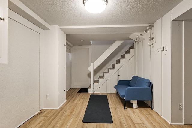 358 Lexington St Unit 358, Watertown, MA 02472 - basement with light wood-type flooring, stairway, and a textured ceiling