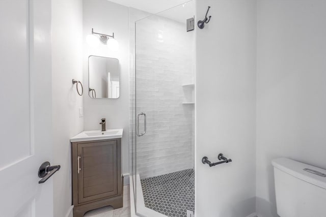 bathroom featuring toilet, a shower stall, and vanity