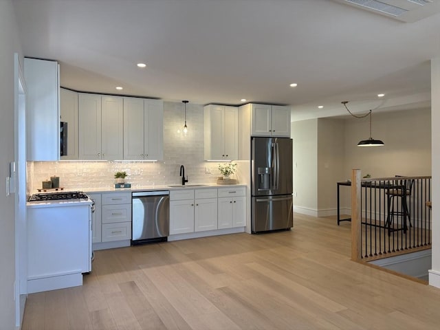 kitchen featuring light wood finished floors, light countertops, stainless steel dishwasher, a sink, and fridge with ice dispenser