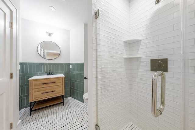 bathroom with toilet, vanity, tile walls, wainscoting, and a shower stall