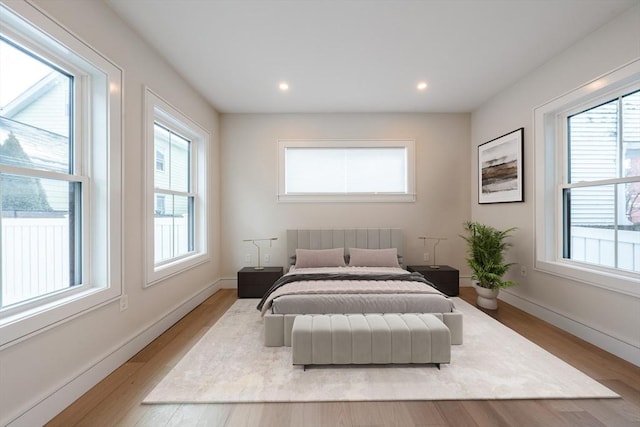 bedroom with recessed lighting, multiple windows, baseboards, and wood finished floors