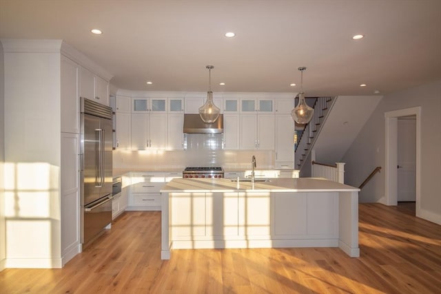 533 Woods Hole Rd Unit B102, Falmouth, MA 02543 - kitchen with built in refrigerator, range, extractor fan, white cabinetry, and a center island with sink