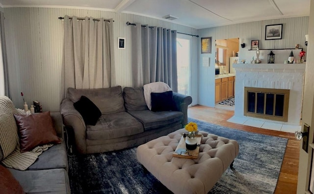 living room with visible vents, light wood-style floors, a fireplace, and crown molding