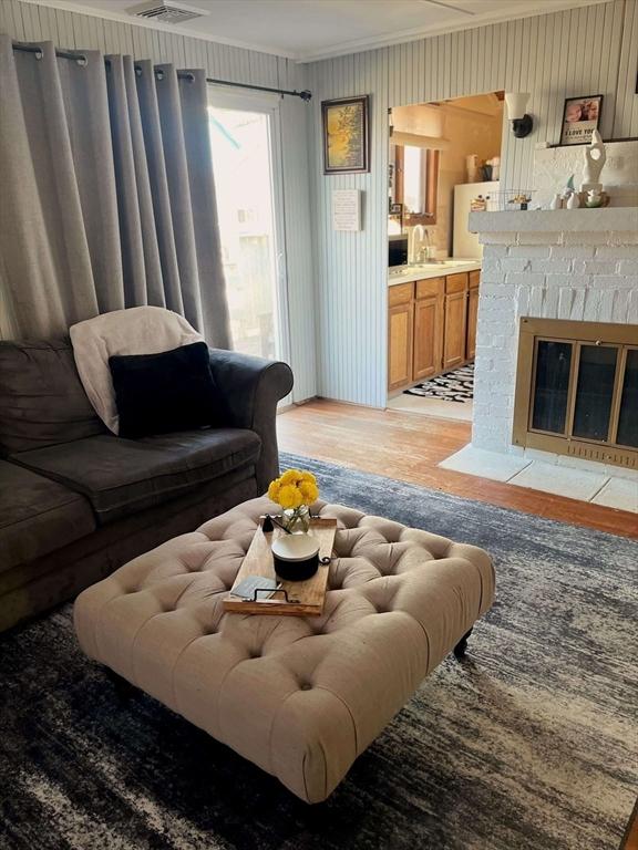 living room with light wood-style floors, a fireplace, and crown molding