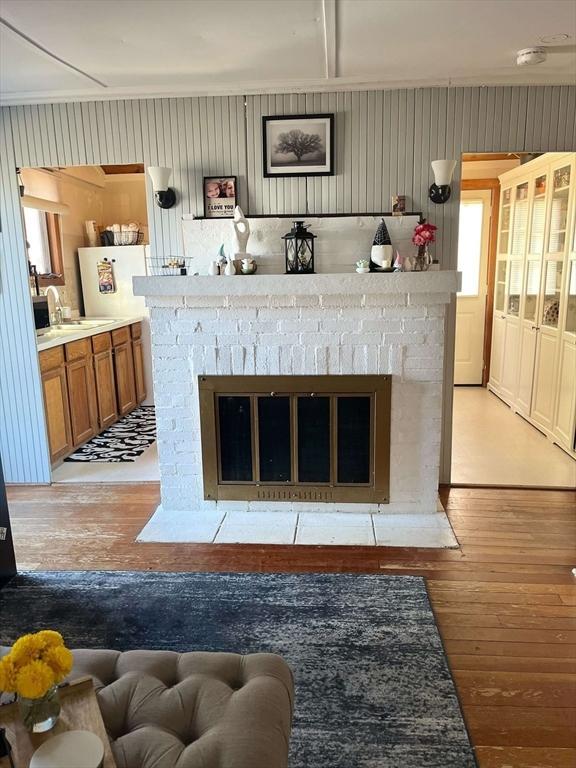 interior details with a sink, a brick fireplace, and wood finished floors