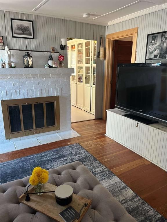 living area featuring a brick fireplace and wood finished floors