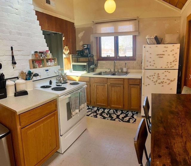 kitchen with light countertops, vaulted ceiling, brown cabinetry, white appliances, and a sink