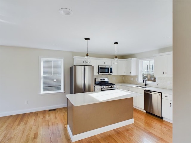 kitchen with pendant lighting, white cabinets, stainless steel appliances, and a kitchen island