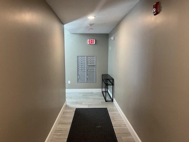 hall with mail area, light wood-style floors, and baseboards
