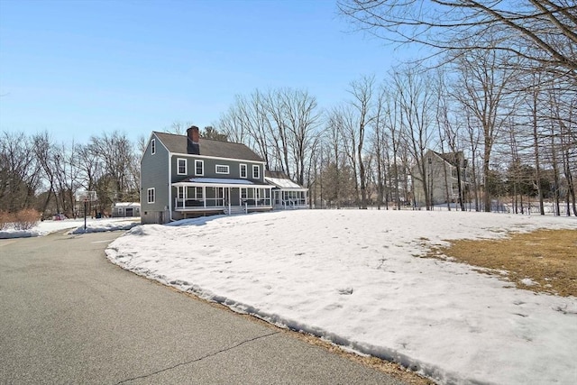 view of front facade with a chimney and a sunroom