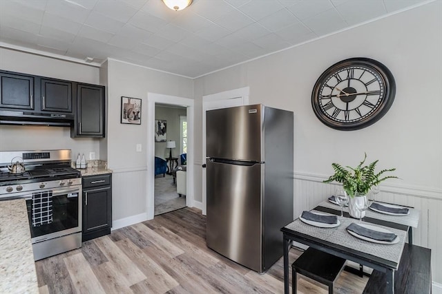 33-35 Claremont St, Springfield, MA 01108 - kitchen featuring stainless steel appliances, under cabinet range hood, light wood-style flooring, a wainscoted wall, and dark cabinets