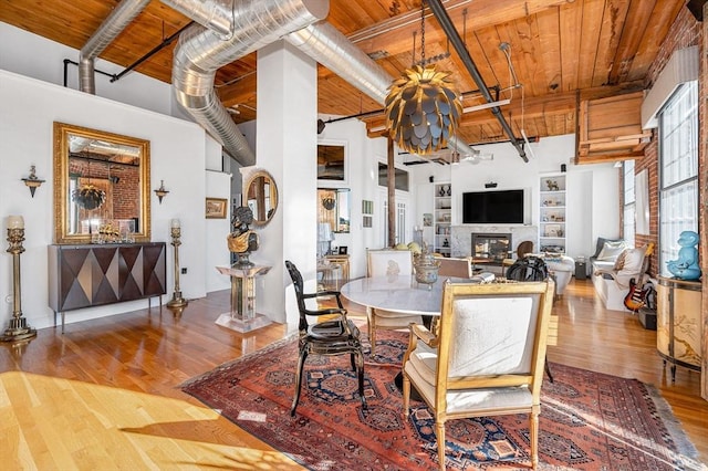 dining area with hardwood / wood-style flooring, wood ceiling, and a towering ceiling