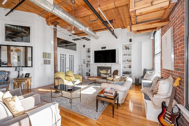 living room with beam ceiling, light hardwood / wood-style floors, wood ceiling, and a premium fireplace