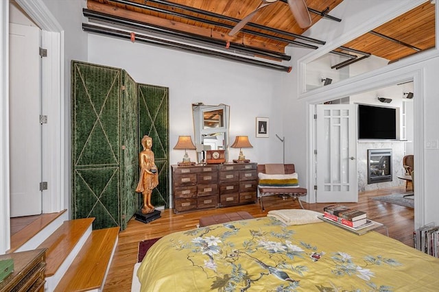 bedroom with a fireplace, hardwood / wood-style floors, and wood ceiling