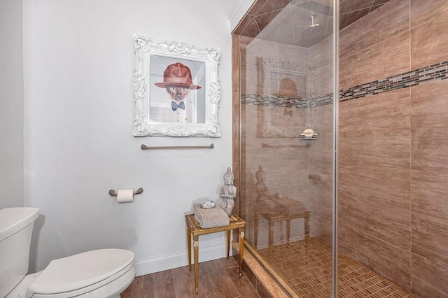 bathroom with hardwood / wood-style flooring, toilet, and tiled shower