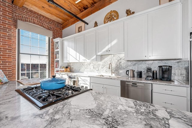 kitchen with beamed ceiling, light stone countertops, sink, and appliances with stainless steel finishes