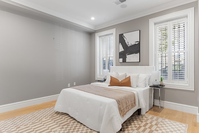 bedroom with multiple windows, crown molding, and light hardwood / wood-style flooring