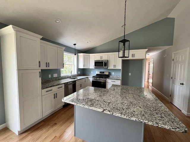 kitchen featuring decorative light fixtures, light wood-type flooring, appliances with stainless steel finishes, a kitchen island, and white cabinets