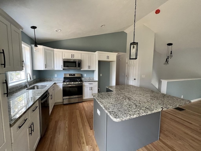 kitchen featuring decorative light fixtures, sink, white cabinets, a center island, and stainless steel appliances