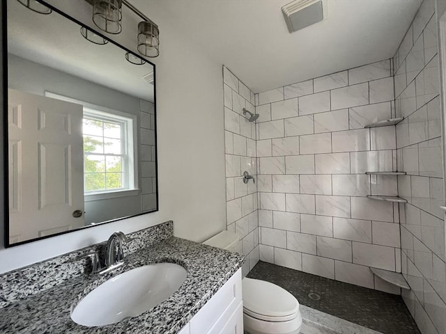 bathroom featuring vanity, toilet, and tiled shower