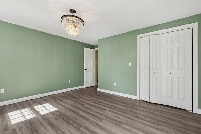 89 Brush Hill Rd, Sherborn, MA 01770 - unfurnished bedroom with baseboards, a closet, wood finished floors, and a notable chandelier