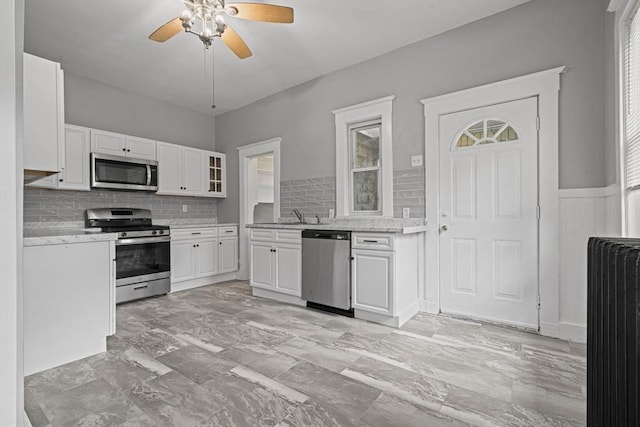 50 Switzer Ave, Springfield, MA 01109 - kitchen with appliances with stainless steel finishes, radiator, ceiling fan, white cabinetry, and decorative backsplash