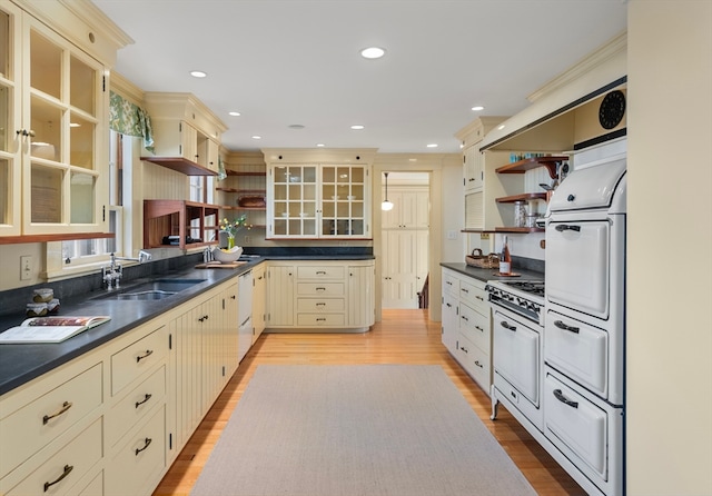 kitchen with cream cabinets, gas range gas stove, sink, and light hardwood / wood-style floors