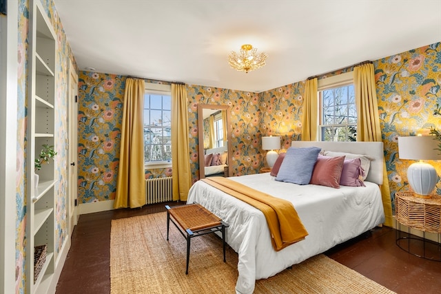 bedroom featuring hardwood / wood-style floors, a notable chandelier, radiator heating unit, and multiple windows