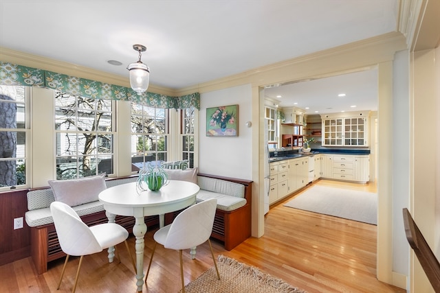 dining area with light wood-type flooring, ornamental molding, a healthy amount of sunlight, and sink