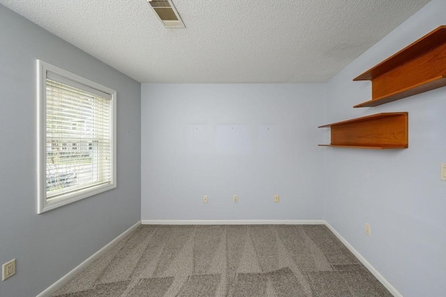 carpeted spare room with visible vents, a textured ceiling, and baseboards