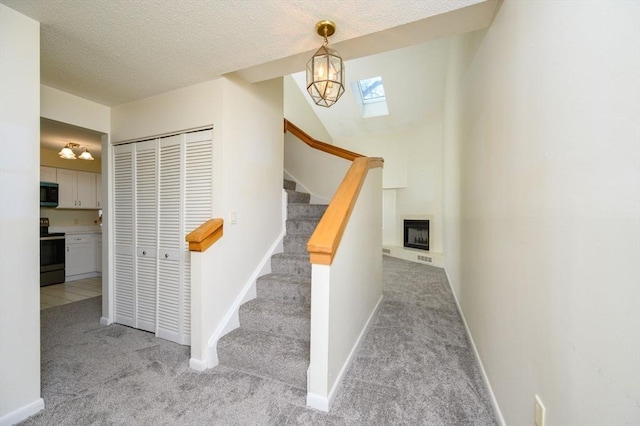 stairs featuring carpet floors, a textured ceiling, baseboards, and a skylight