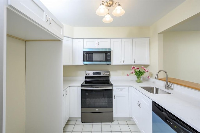kitchen featuring appliances with stainless steel finishes, a sink, light countertops, a chandelier, and white cabinetry