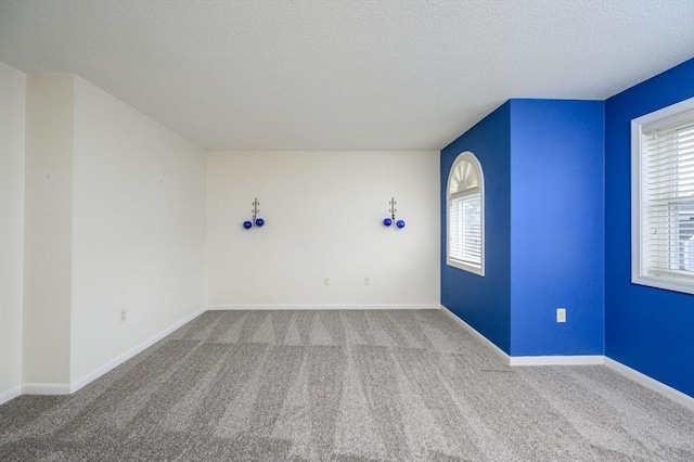 empty room with baseboards, a textured ceiling, and carpet