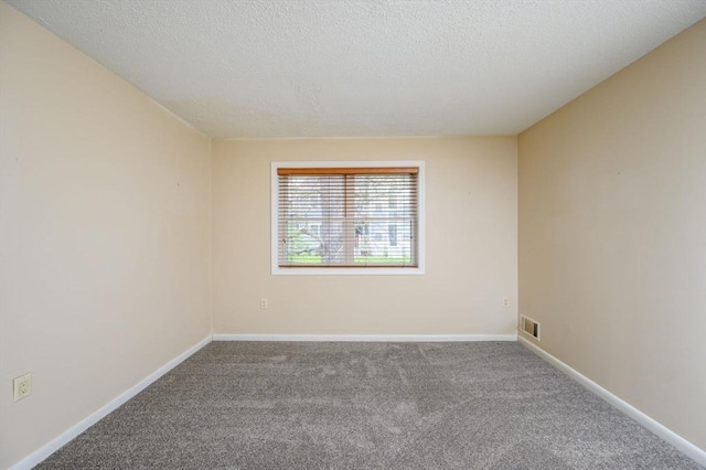 empty room featuring visible vents, a textured ceiling, carpet, and baseboards