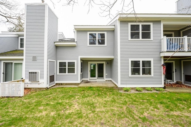 rear view of property featuring a lawn, a balcony, and a chimney