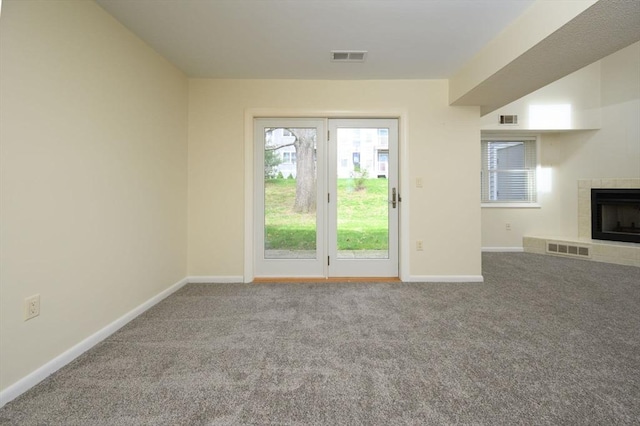 unfurnished living room with carpet flooring, baseboards, visible vents, and a fireplace