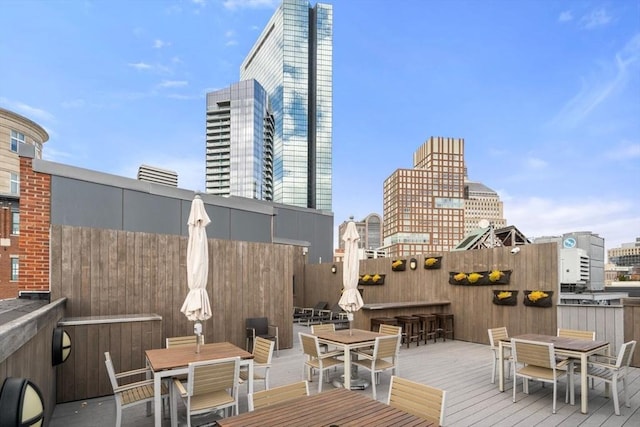 wooden deck featuring a view of city, outdoor dry bar, and outdoor dining area