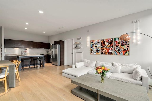 living room with light wood-style floors, visible vents, and recessed lighting