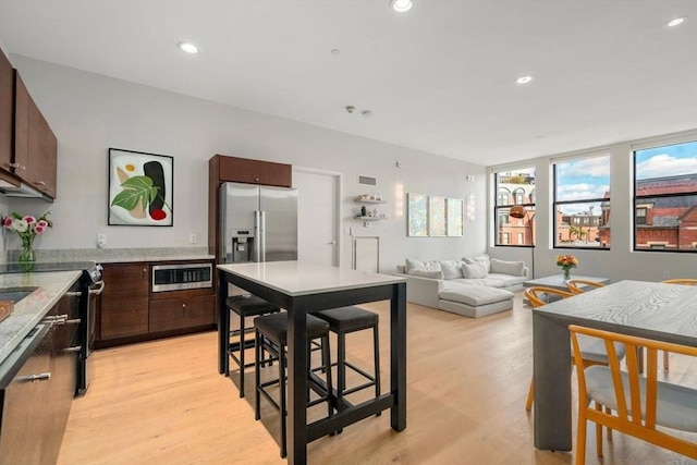 kitchen with light wood-type flooring, dark brown cabinetry, recessed lighting, and stainless steel fridge with ice dispenser