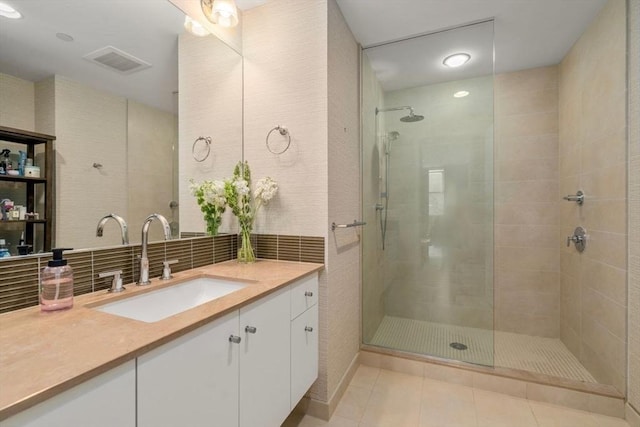 full bathroom with tasteful backsplash, visible vents, tile patterned flooring, a tile shower, and vanity