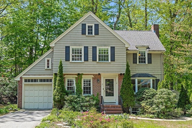 view of front of property featuring entry steps, a chimney, asphalt driveway, brick siding, and an attached garage